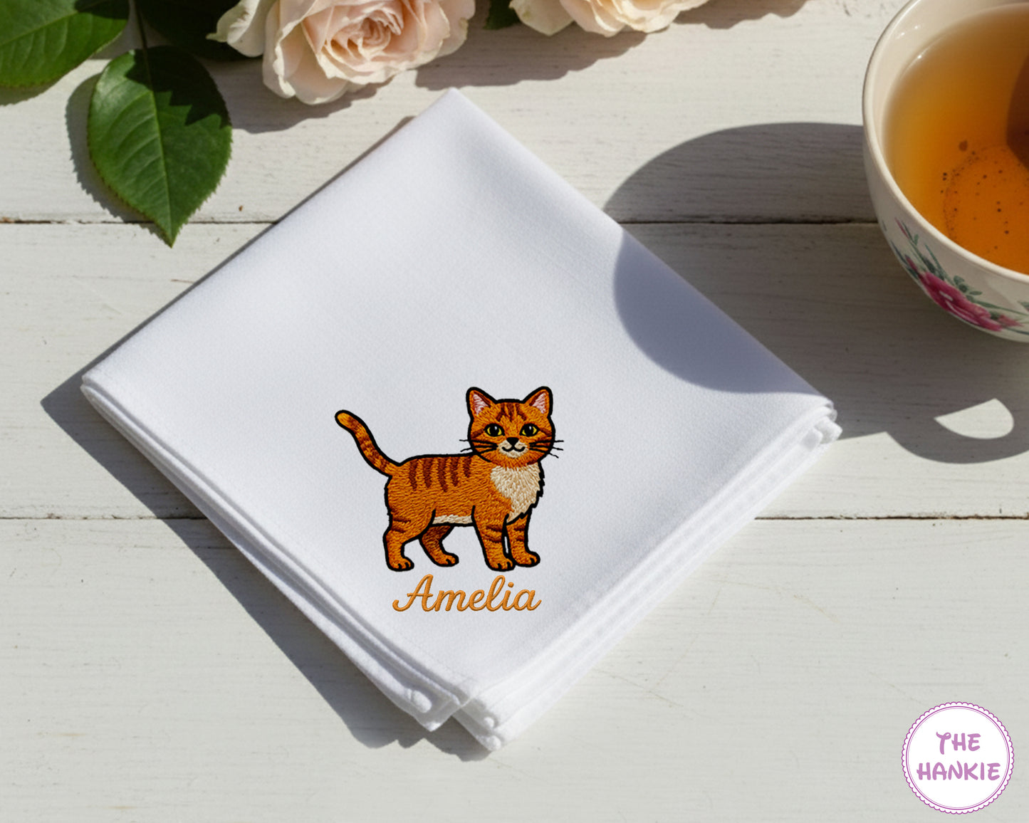 A soft sky blue cotton handkerchief personalized with the name "amelia" and an embroidered cat character.