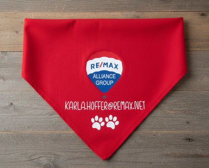 A vibrant red dog bandana featuring the Remax Alliance Group hot air balloon logo and a custom contact email in white vinyl.
