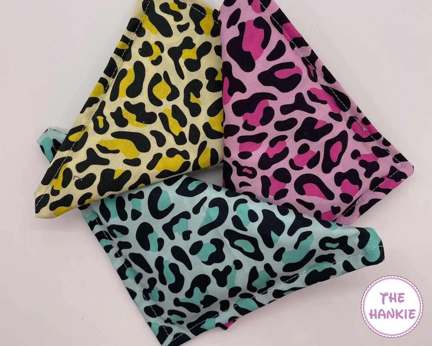 Three colorful hankies with leopard print patterns on a light background, branded 'The Hankie'.
