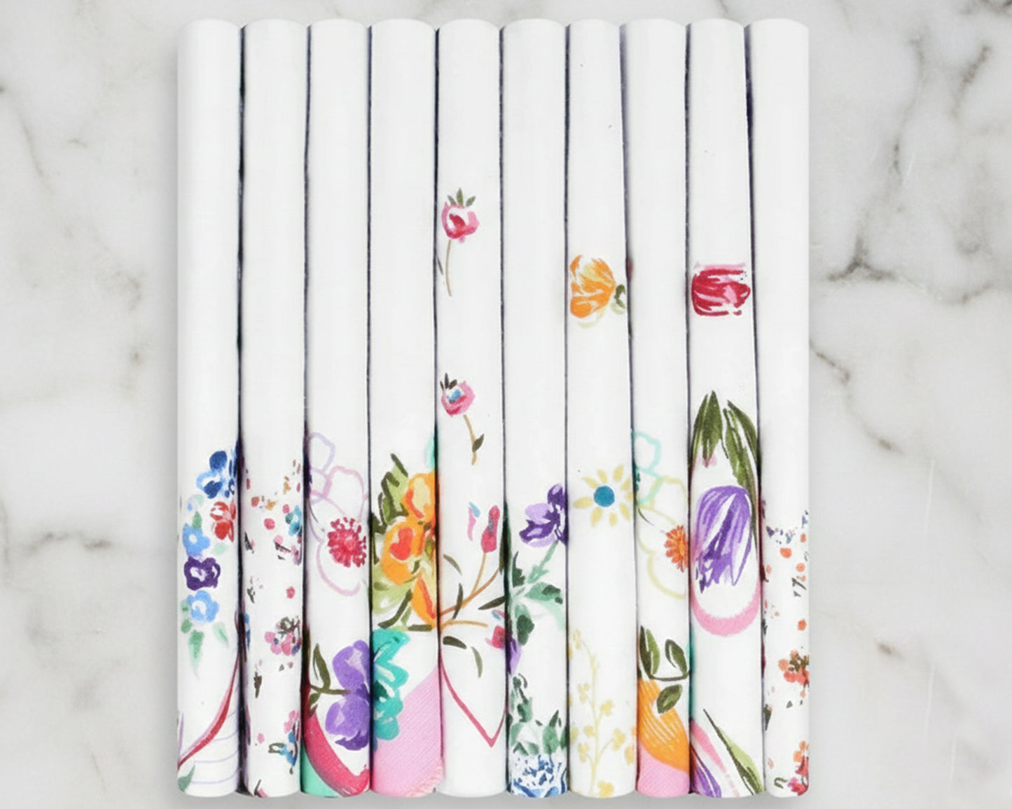 Set of white hankies rolls with colorful floral patterns on a marble surface