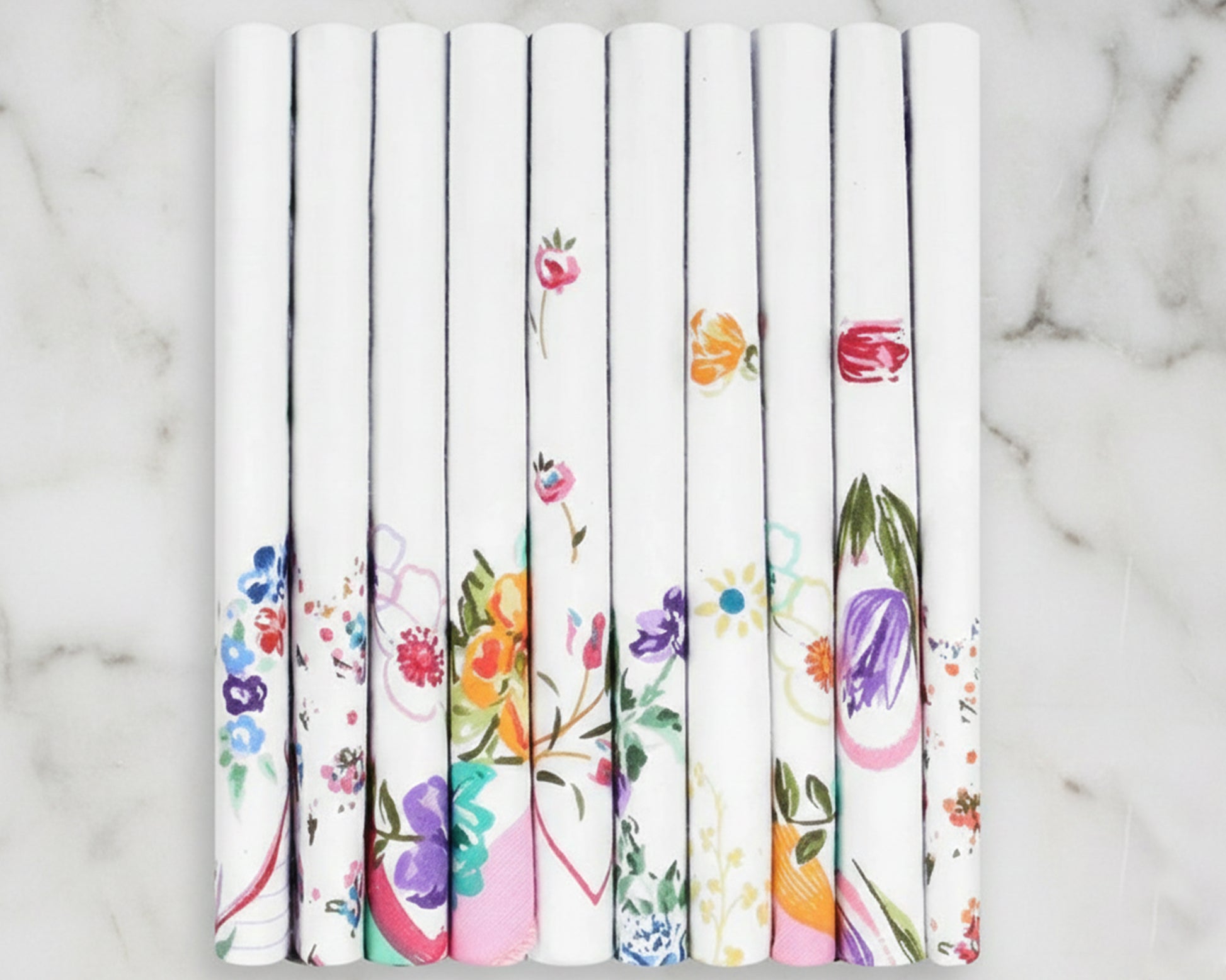 Set of white hankies rolls with colorful floral patterns on a marble surface