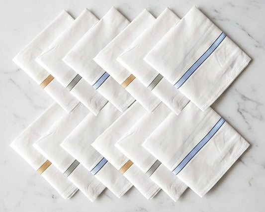 Set of white hankies with blue and gold accents on a marble surface