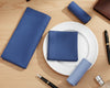 Blue napkins on a white plate with stationery items on a wooden surface