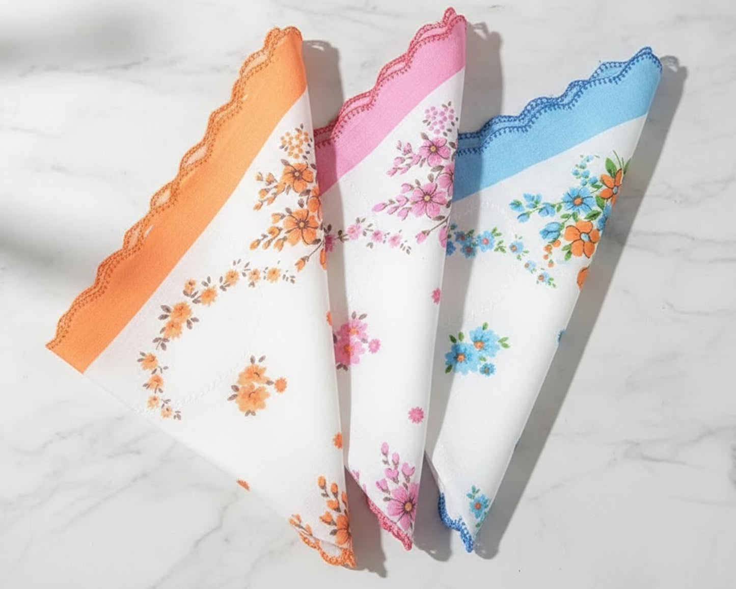 Three floral handkerchiefs in orange, pink, and blue on a white background
