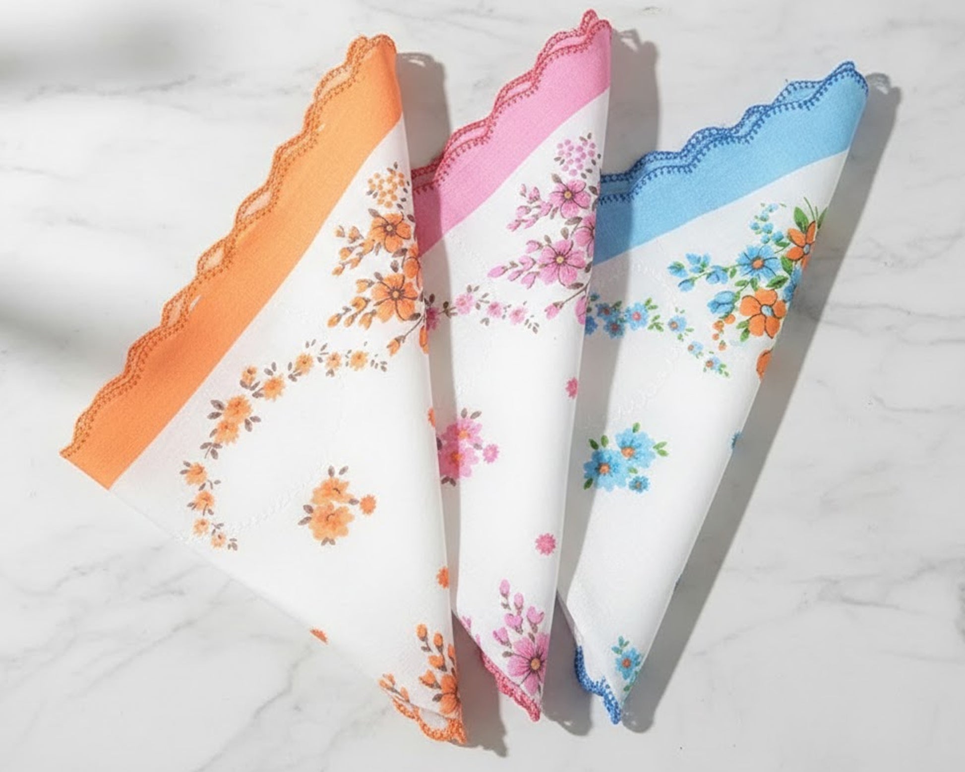 Three floral handkerchiefs in orange, pink, and blue on a white background
