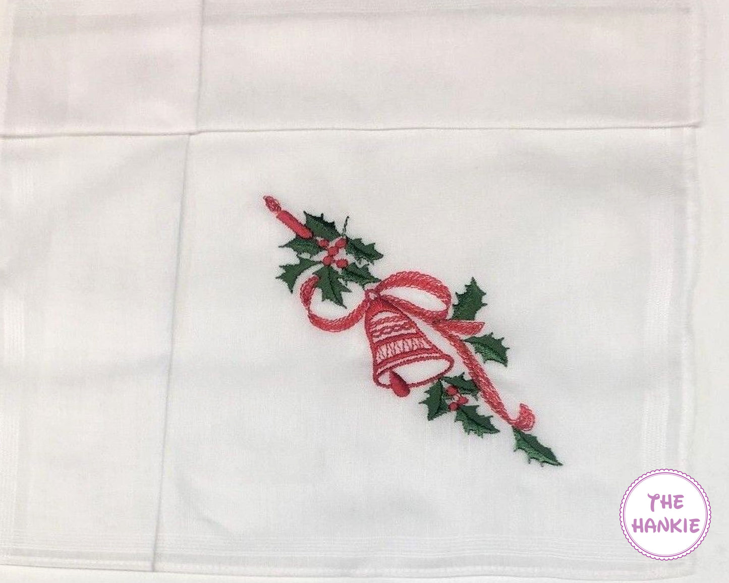 White hankie with embroidered red bell and green holly design, featuring 'The Hankie' brand.