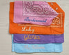 Close-up flat lay of personalized "Mrs. Williams" and "Bridesmaid" bandanas on a light wood background with tropical shadows.
