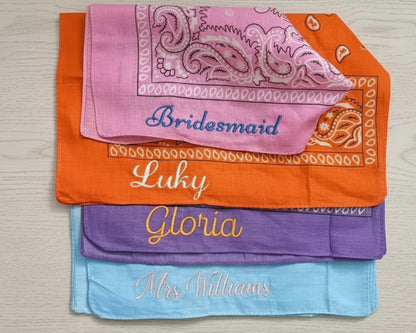 Close-up flat lay of personalized "Mrs. Williams" and "Bridesmaid" bandanas on a light wood background with tropical shadows.