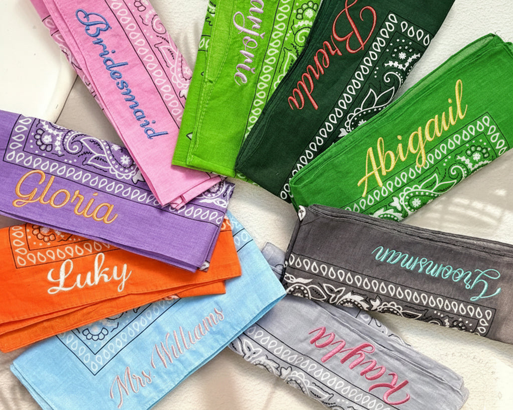 Colorful bandanas with personalized names arranged on a white surface