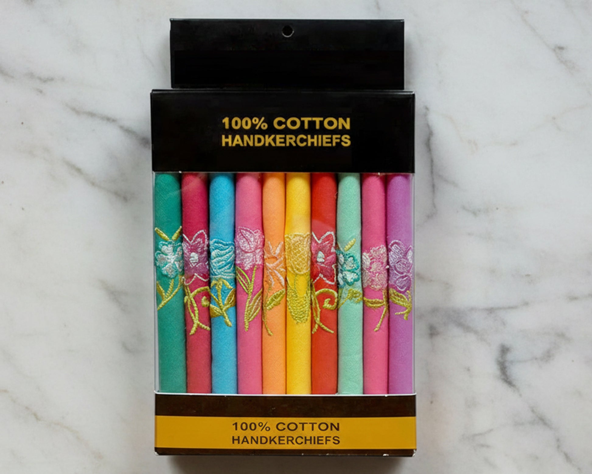 Pack of colorful handkerchiefs with floral designs in a black box on a marble background
