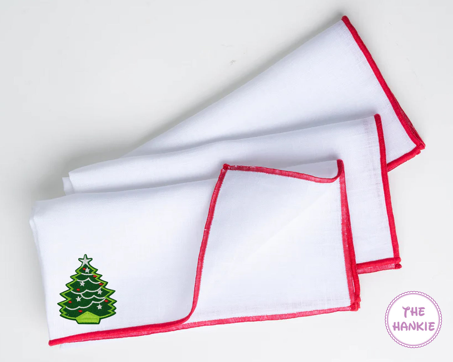 White hankie with red trim featuring a nutcracker design, branded 'The Hankie'.