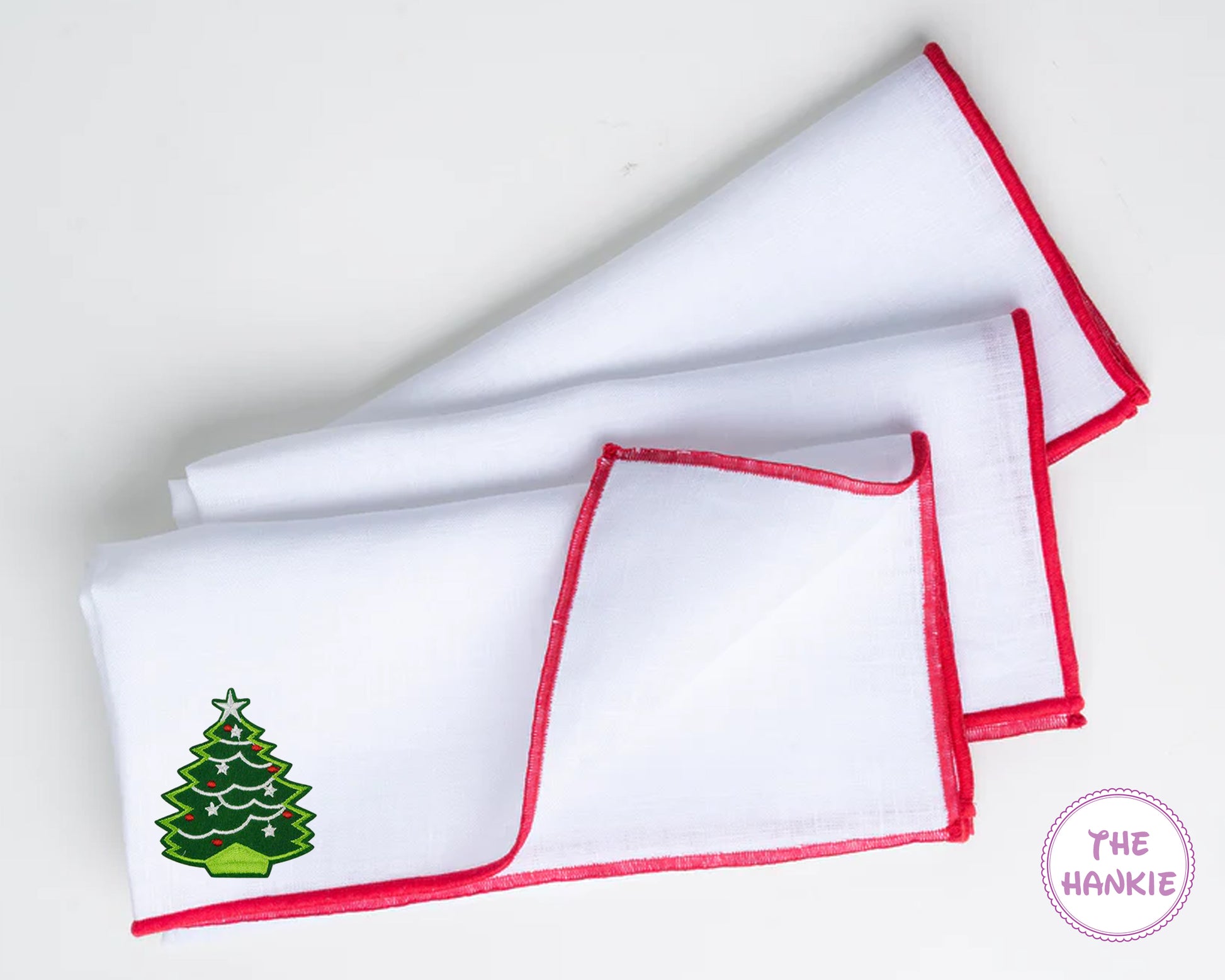 White hankie with red trim featuring a nutcracker design, branded 'The Hankie'.