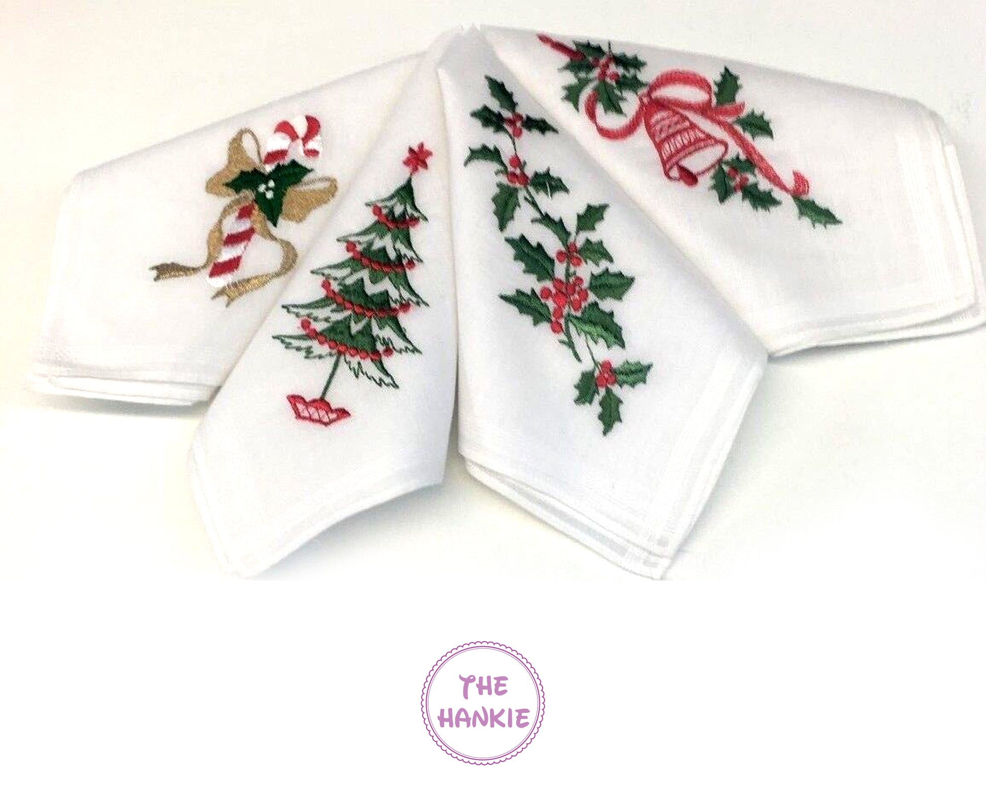 Set of four white hankies with Christmas-themed embroidery on a white background.