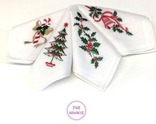 Set of four white hankies with Christmas-themed embroidery on a white background.