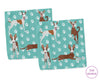Two folded towels with dog pattern on a teal background, featuring 'The Hankie' brand.