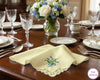 Dining table set with glasses, plates, and a vase of flowers on a wooden table.