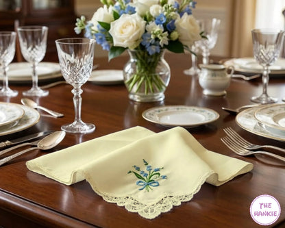 Dining table set with glasses, plates, and a vase of flowers on a wooden table.