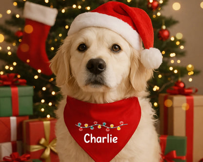 Dog wearing a Santa hat and red bandana with 'Charlie' on, in front of a Christmas tree and presents.