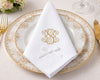 Elegant table setting with a white napkin featuring a gold monogram on a decorative plate.