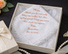 Embroidered handkerchief in a box with personalized message, surrounded by decorative items.