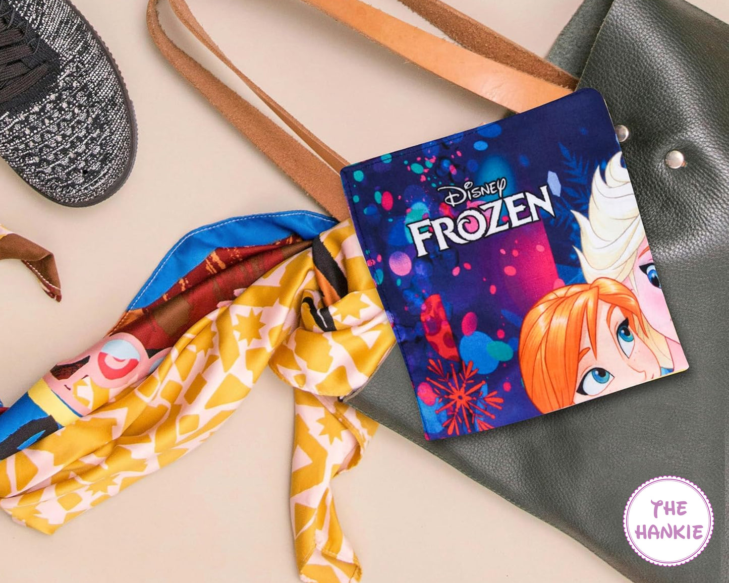 Disney Frozen-themed hankie on a handbag with colorful scarf and hat in the background