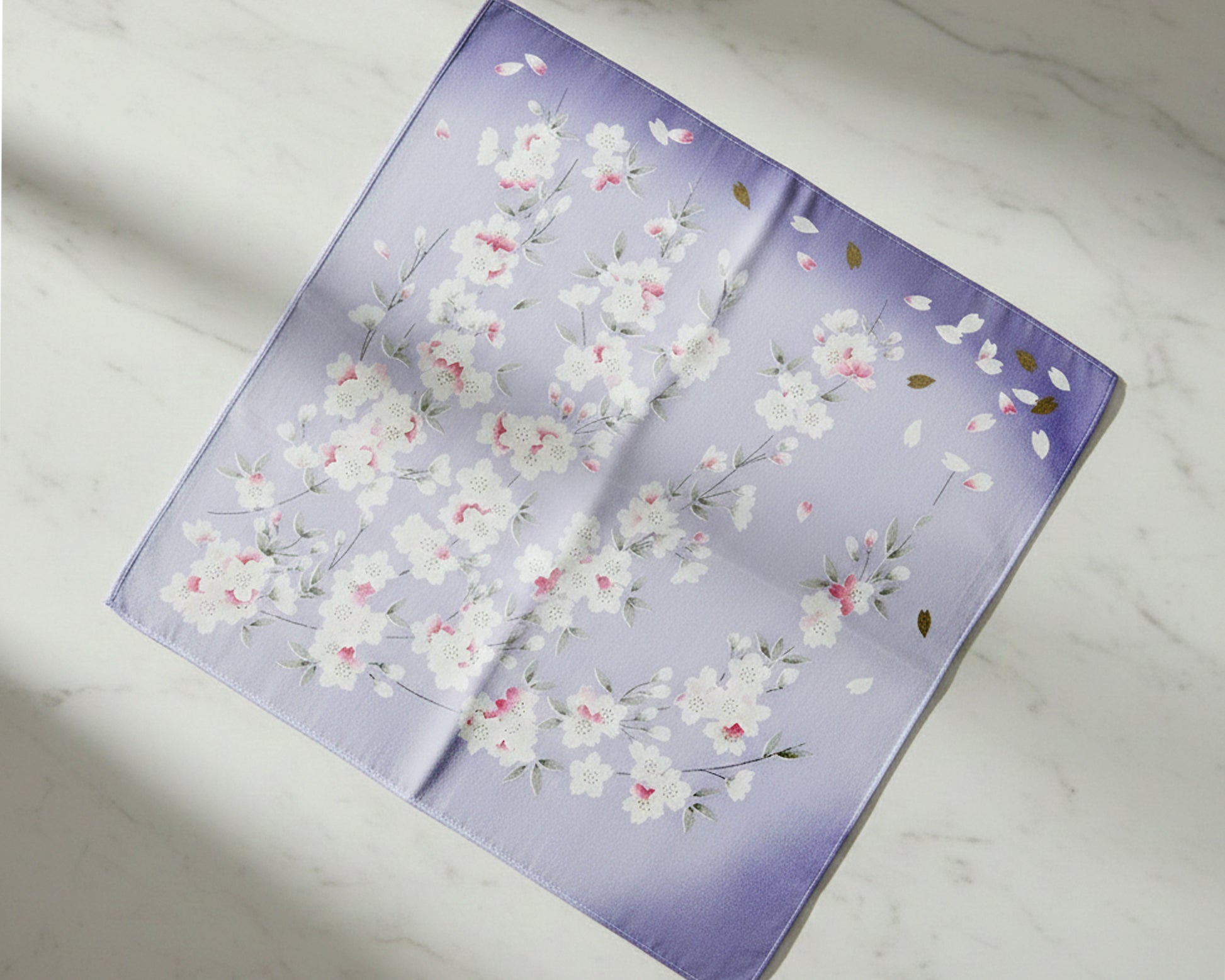 Floral patterned fabric square hankie on a light marble background