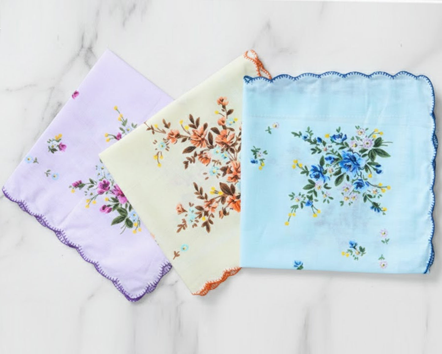 Three floral handkerchiefs in purple, yellow, and blue on a light background