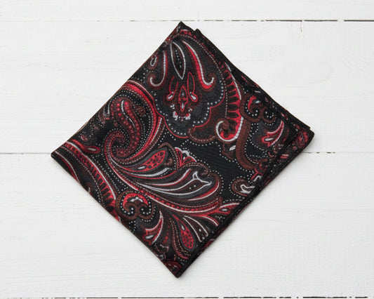 Folded red and black paisley patterned fabric on a white wooden surface