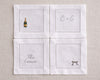 Four white napkins with embroidered designs on a beige background
