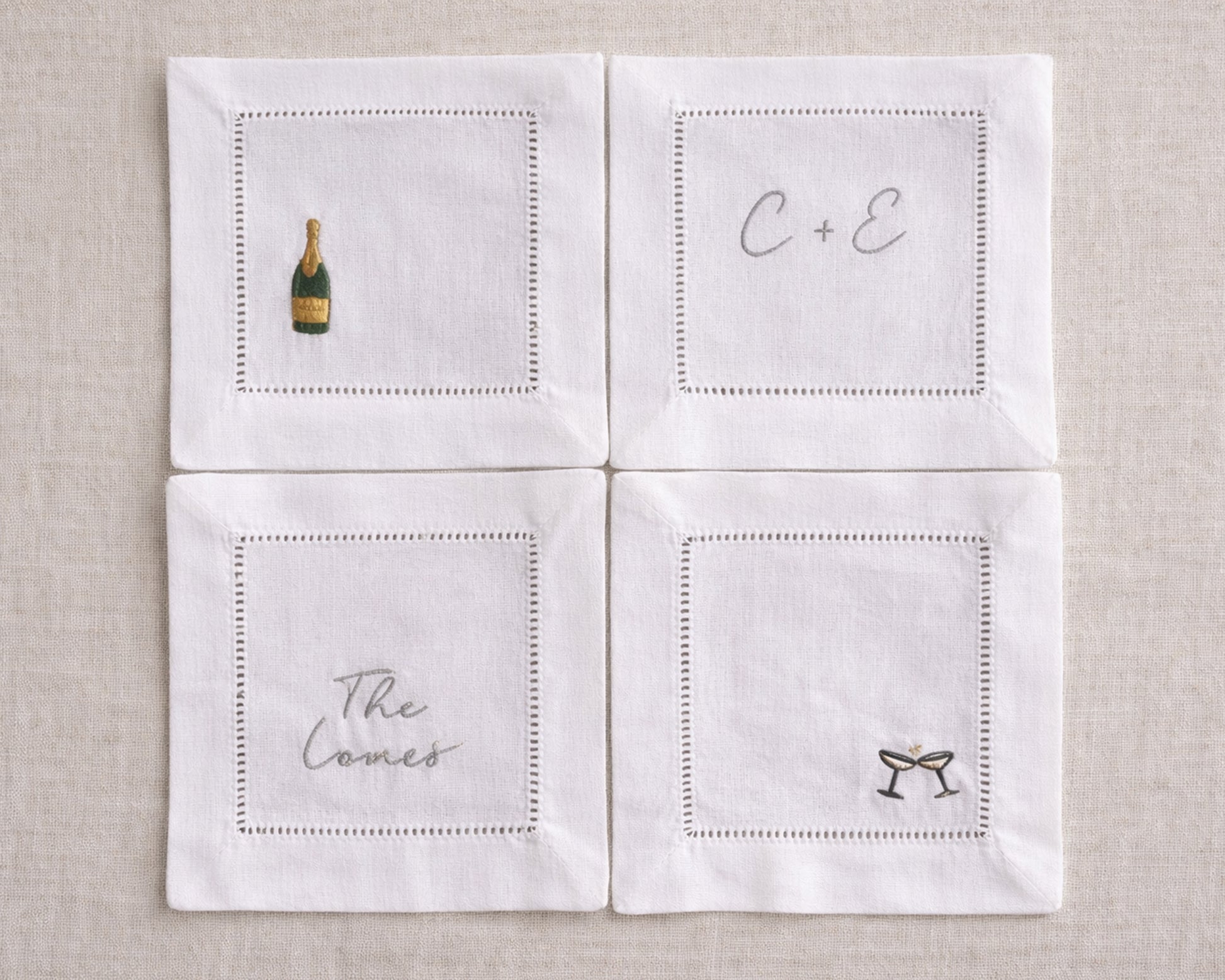 Four white napkins with embroidered designs on a beige background