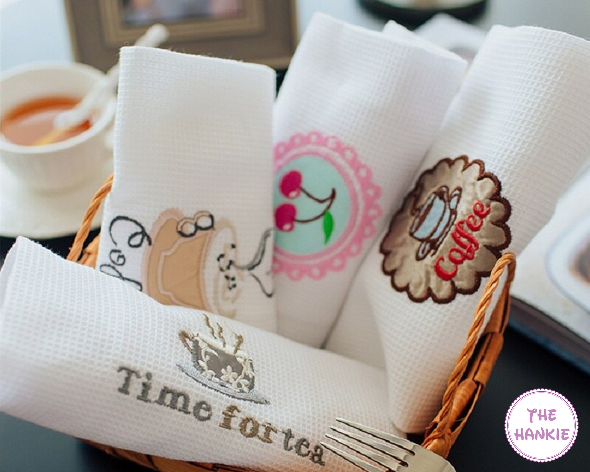 Set of embroidered napkins with coffee and tea designs in a basket.