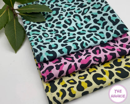 Three fabric hankies with leopard print patterns on a white surface, branded 'The Hankie'.