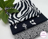 Three black and white patterned hankies on a white surface with a leafy branch.