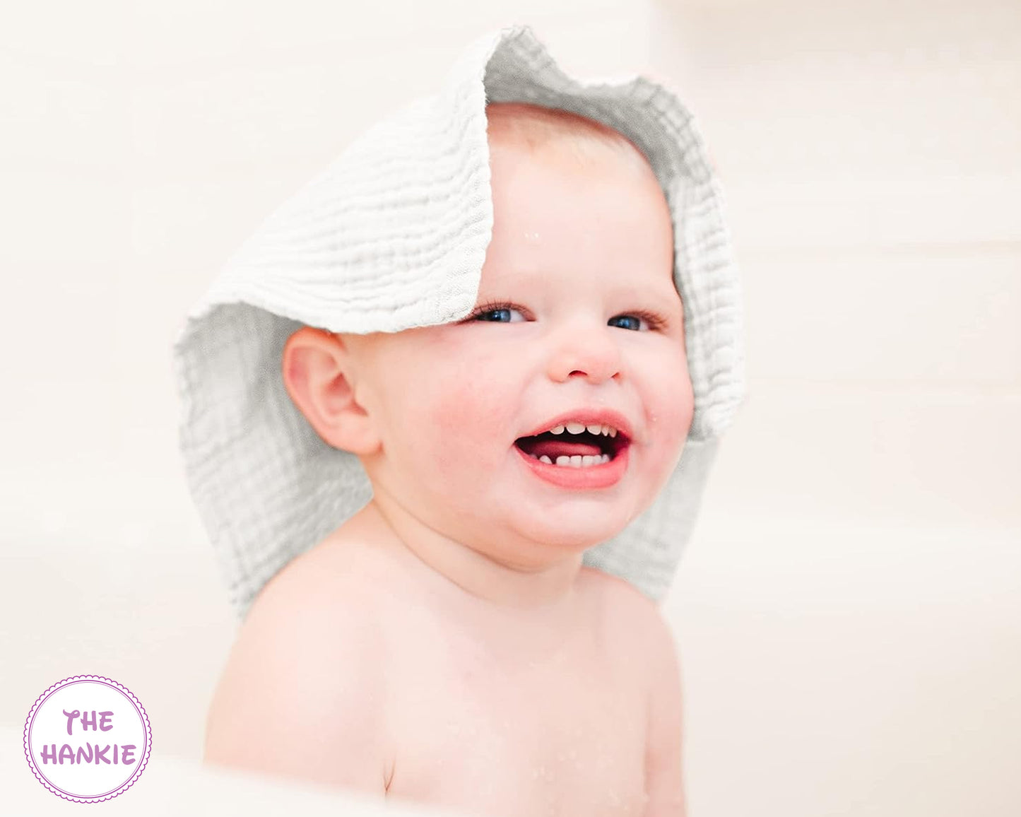 Baby wearing a white hooded towel with 'The Hankie' logo.
