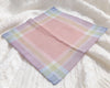Pastel plaid fabric on a textured white surface