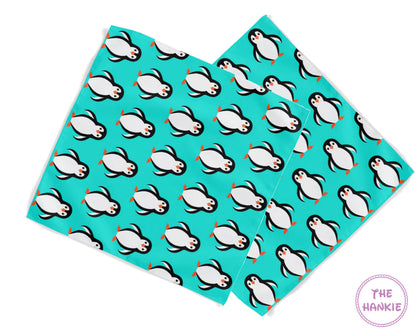 Two hankies with penguin pattern on a turquoise background, branded 'The Hankie'.
