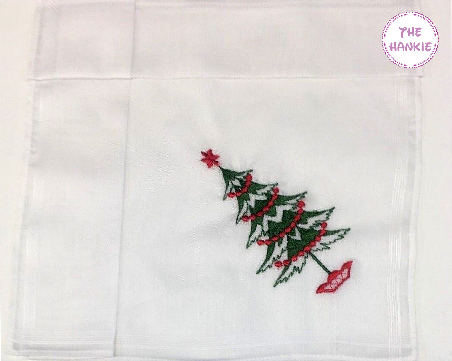 White hankie with a embroidered Christmas tree design on a white background