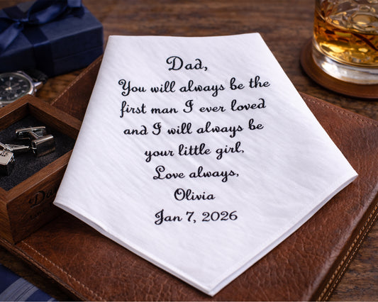 Personalized handkerchief with a heartfelt message on a wooden surface with a glass of whiskey and jewelry box.