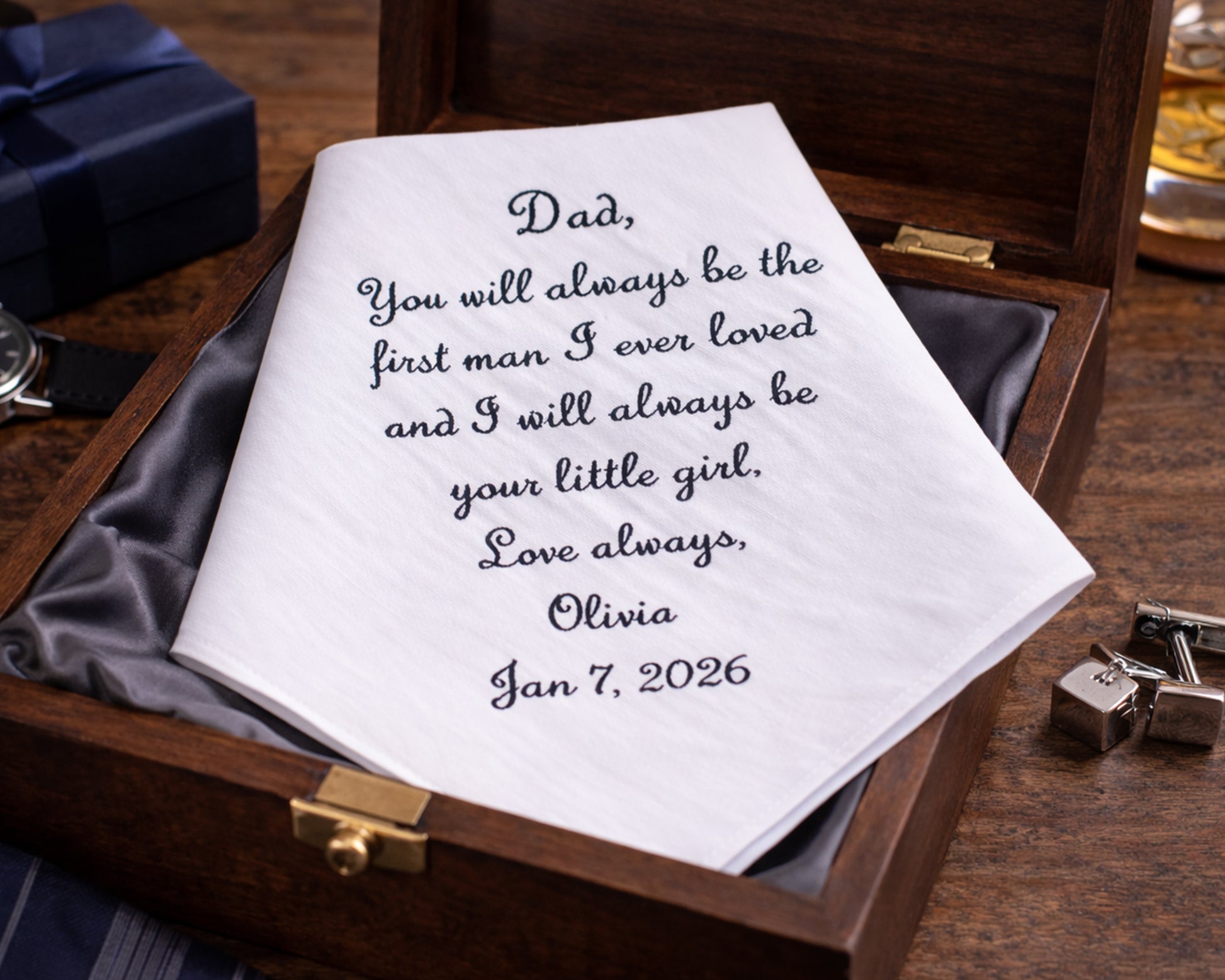 Personalized handkerchief with embroidered message in a wooden box on a wooden surface.
