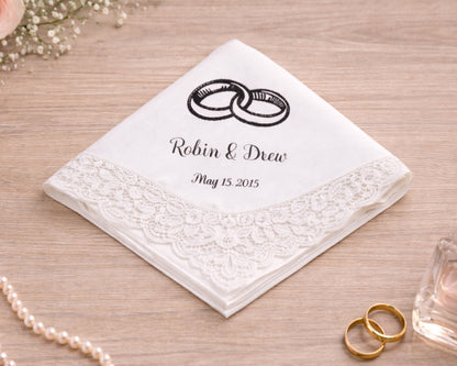 Personalized handkerchief with wedding rings design and text on a wooden surface.