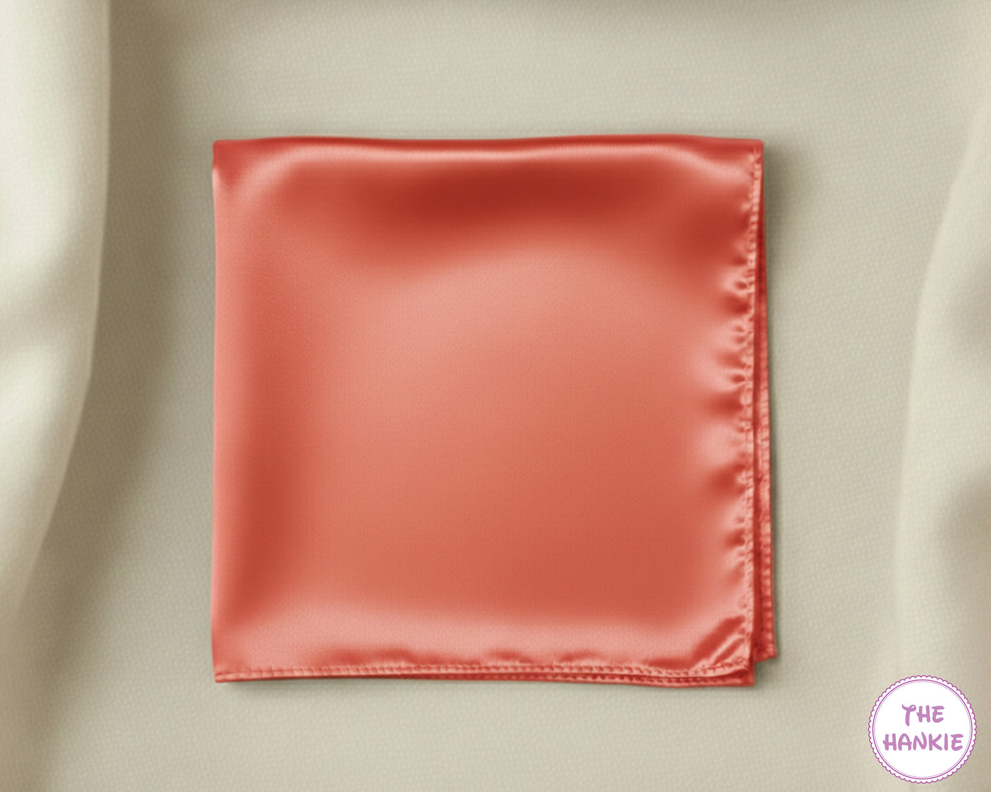 Red satin hankie on a beige fabric background with 'The Hankie' brand logo.