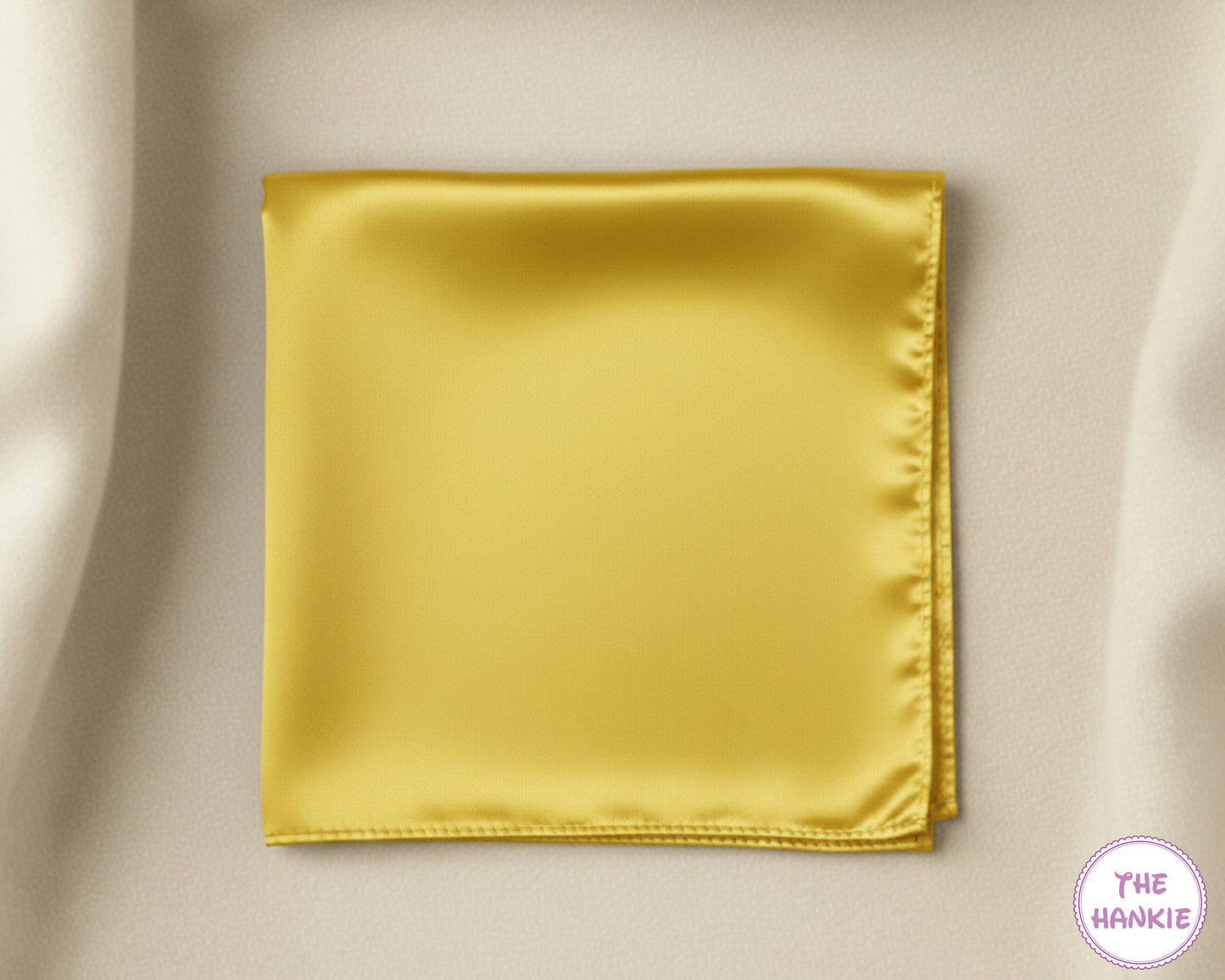 Gold satin pocket square on a beige fabric background