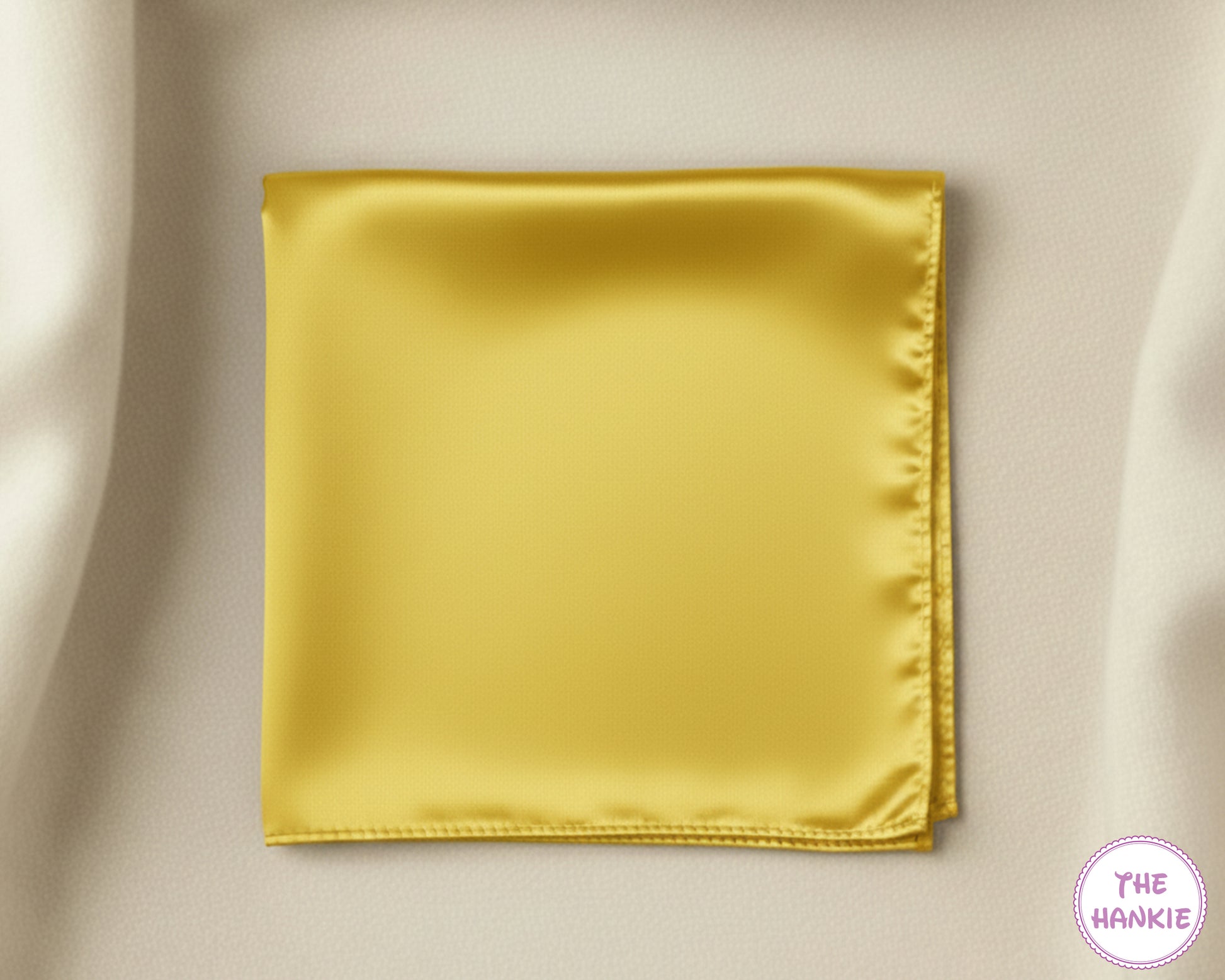 Gold satin pocket square on a beige fabric background