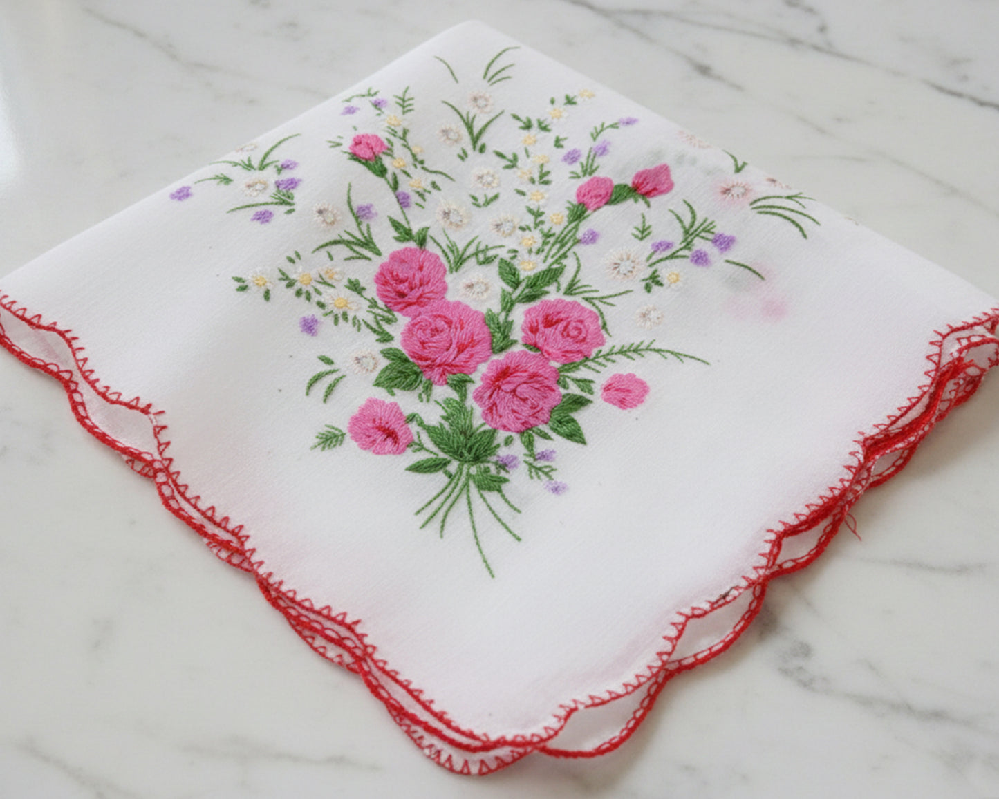 Embroidered handkerchief with pink roses on a marble surface