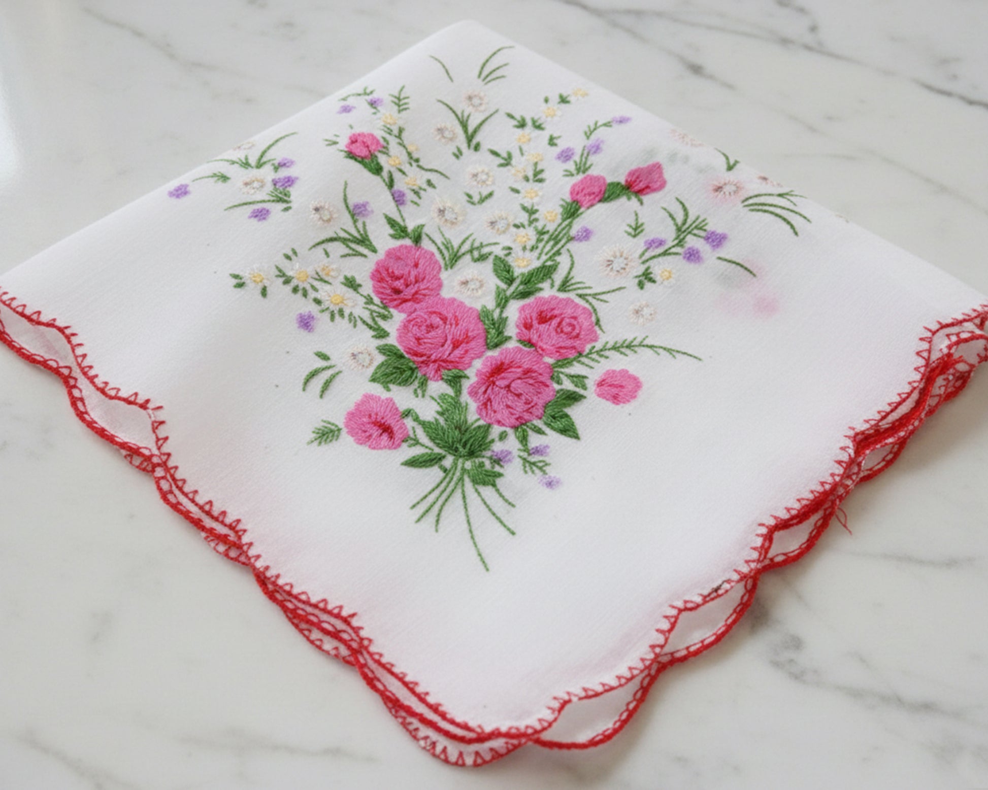 Embroidered handkerchief with pink roses on a marble surface