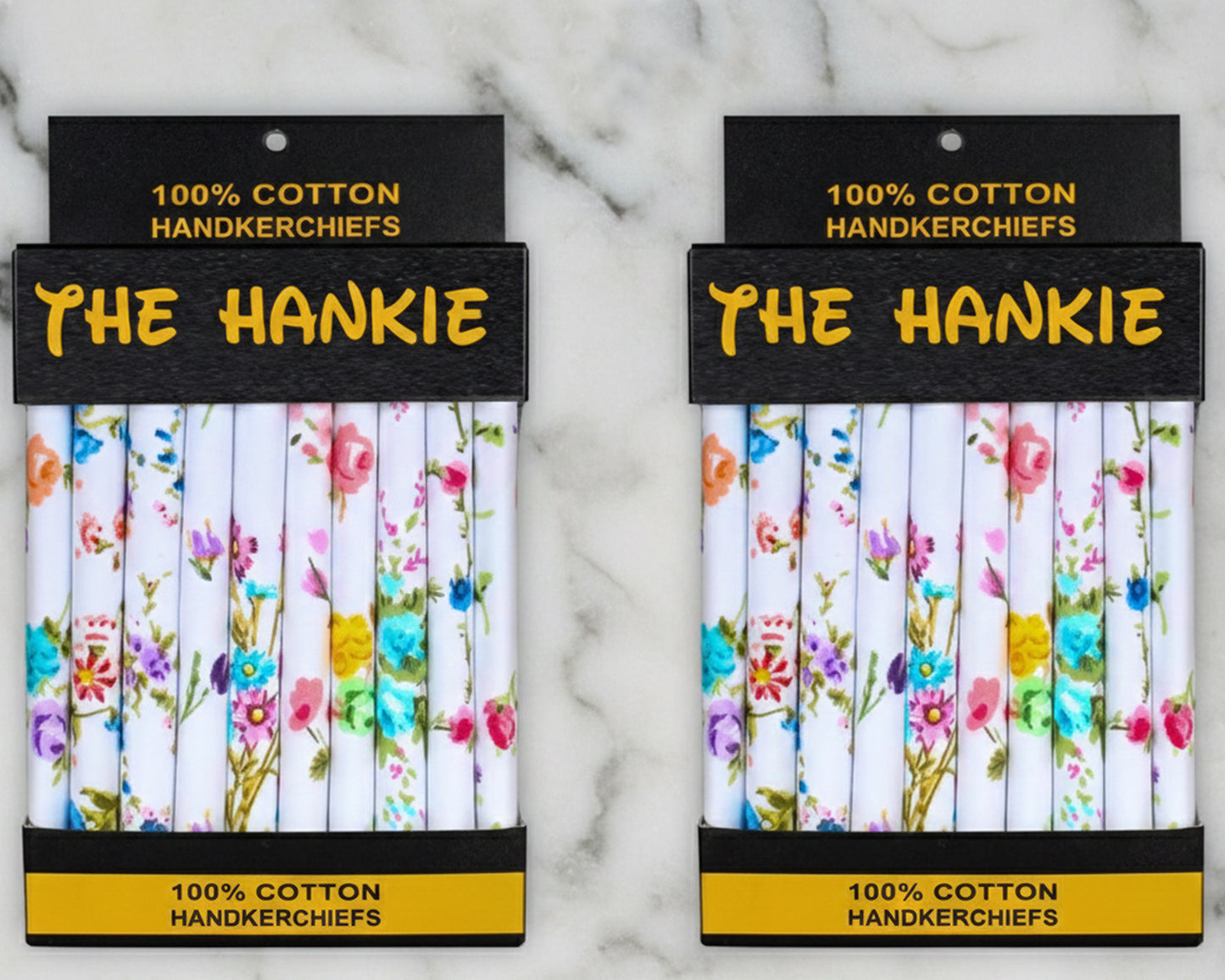 Two packages of 'The Hankie' 100% cotton handkerchiefs with floral designs on a marble background.