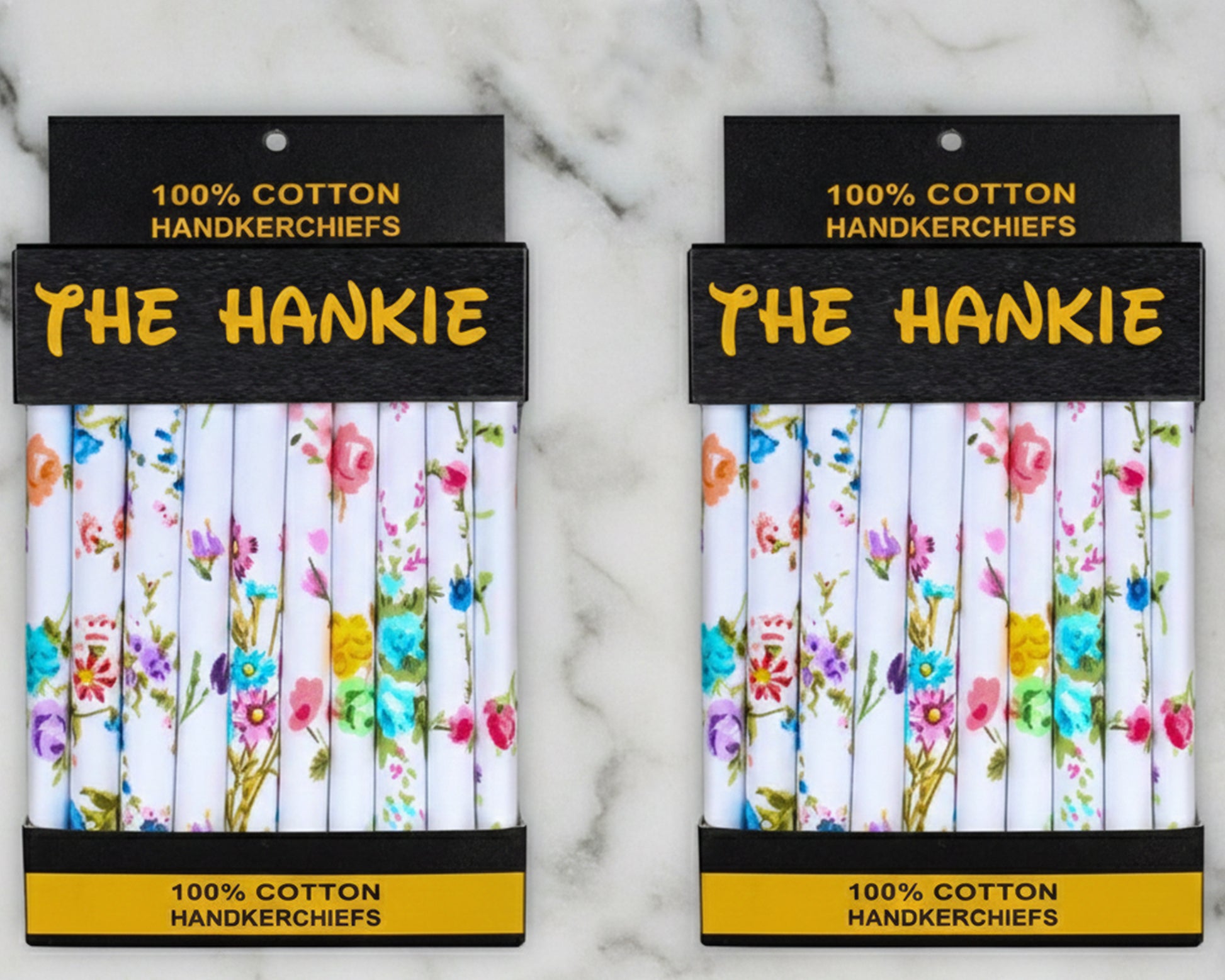Two packages of 'The Hankie' 100% cotton handkerchiefs with floral designs on a marble background.
