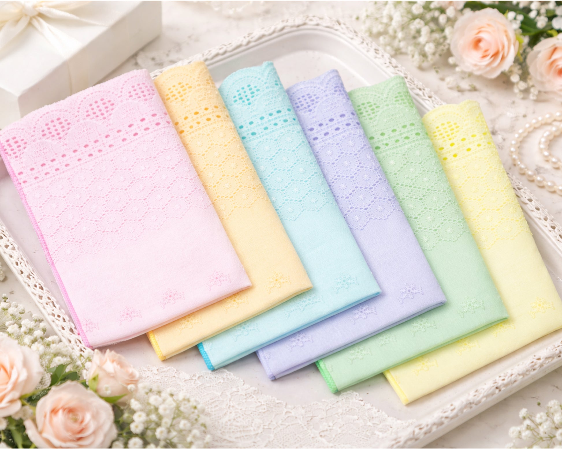 Set of pastel-colored handkerchiefs on a decorative tray with flowers.