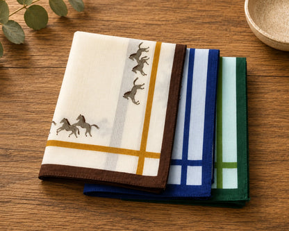 Set of folded hankies with horse designs on a wooden surface