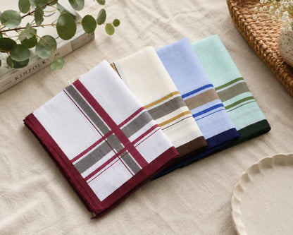 Set of four striped handkerchiefs on a beige surface with a plant and book in the background.
